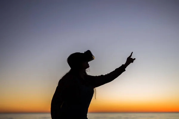 Mujer joven con gafas de realidad virtual en el cielo de fondo sueños hechos realidad — Foto de Stock