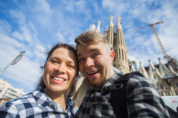 Viajes, vacaciones y concepto de personas - Pareja feliz tomando foto selfie frente a la Sagrada Familia en Barcelona — Foto de Stock