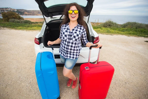 Cestování, cestovní ruch a lidé koncept - šťastná mladá žena bude cestovat autem s dvěma obrovské případů nosí brýle — Stock fotografie