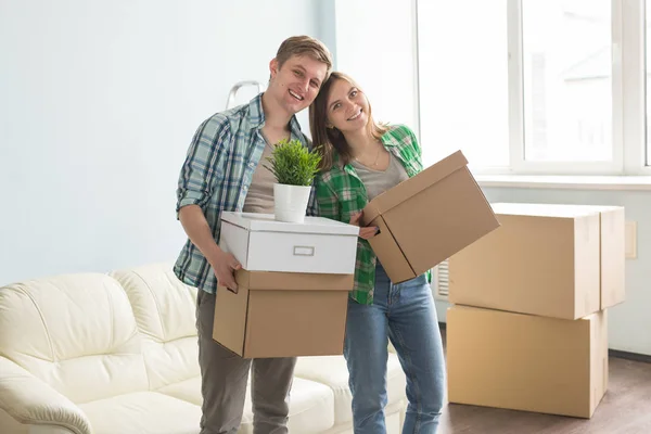 Дом, люди, переезд и концепция недвижимости - счастливая пара веселится и катается в картонных коробках в новом доме — стоковое фото