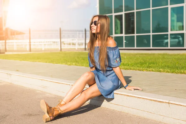 Lifestyle-, Mode- und People-Konzept - Porträt einer schönen jungen Frau mit langen Haaren, die auf der Straße sitzt — Stockfoto