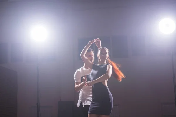 Bailarines hábiles actuando en la sala oscura bajo la luz del concierto y el humo. Pareja sensual realizando una danza contemporánea artística y emocional — Foto de Stock