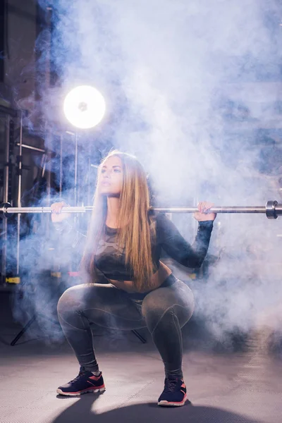 Mujer bonita haciendo ejercicio con barra en un gimnasio — Foto de Stock