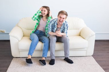 eğlenceli olan genç bir çift kanepede gülüyor.