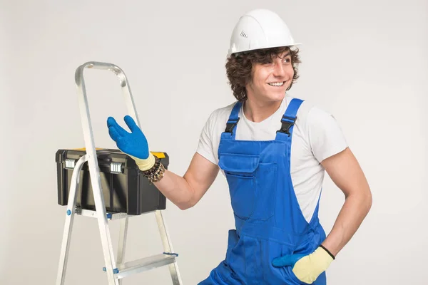 Studio portrait of handsome builder in white helmet and blue overall shaking his hand and laughing. — Stock Photo, Image