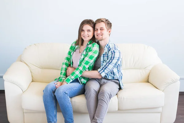 Retrato de um jovem casal amoroso descansando em um sofá juntos em casa e abraçando . — Fotografia de Stock