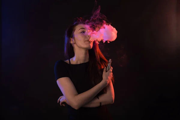 Young woman in black t-shirt vaping in red and blue neon light — Stock Photo, Image