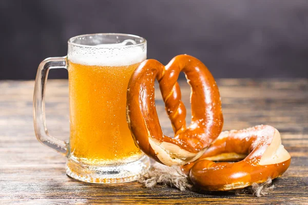 Drink and food concept- Glass of beer and bagels on wood table — Stock Photo, Image