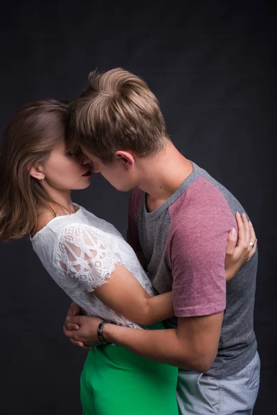 Bonito jovem casal abraçando e beijando isolado no fundo preto . — Fotografia de Stock