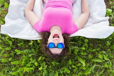 Yaz, tatil ve eğlence kavramı - en iyi genç komik kadın parkta çim üzerinde yalan güneş gözlüğü takıyor portresi