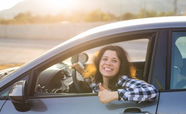 Başparmak gösterilmesini ve yeni bir araba sürüş mutlu kadın