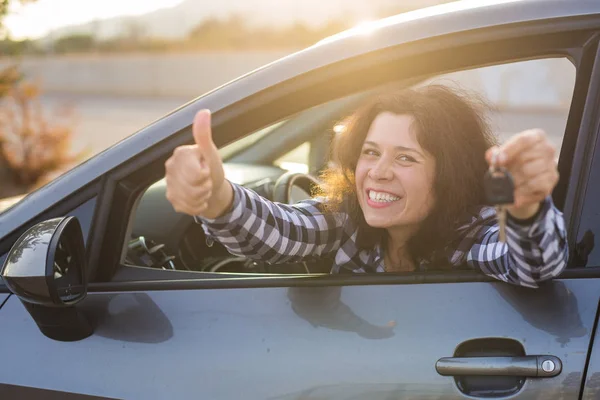 Šťastná dívka v autě ukazuje klíč a palcem nahoru gesto — Stock fotografie