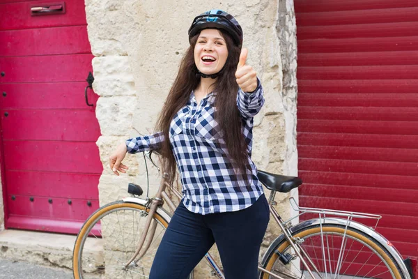 헬멧과 자전거 엄지손가락을 보여주는 젊은 명랑 한 여자 — 스톡 사진