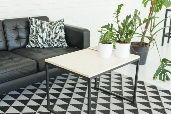 Interior, conceito de mobiliário - uma mesa branca está de pé em uma sala perto do sofá de couro preto — Fotografia de Stock