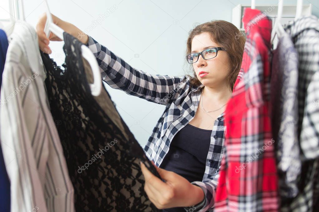 Fashion and people concept - woman choosing clothes in front of full closet.