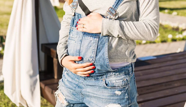 Young pregnant woman holds her hands on her swollen belly. Love concept. — Stock Photo, Image