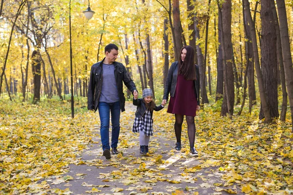 People, family and leisure concept - family with a young daughter walking in autumn park — Stock Photo, Image