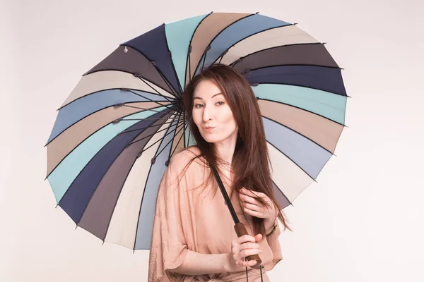 Πορτρέτο του χαριτωμένο γυναίκα της Ασίας κάτω από ομπρέλα ριγέ σε λευκό φόντο — Φωτογραφία Αρχείου
