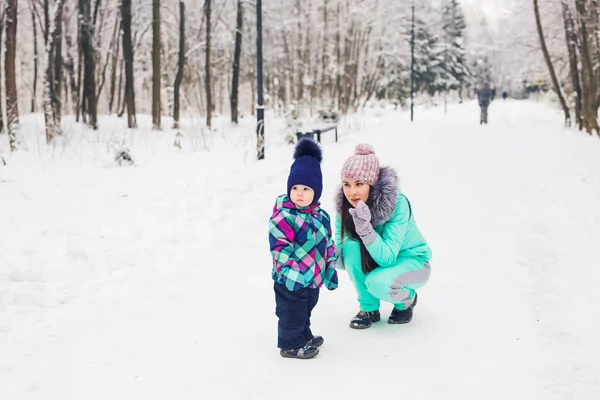 Winter, parents and children concept - mother and daughter walking and having fun on a snowy street — Stock Photo, Image