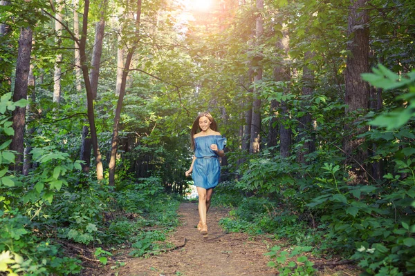 Naturaleza, personas y concepto de estilo de vida - Hermosa mujer joven en vestido corriendo en el bosque de verano —  Fotos de Stock