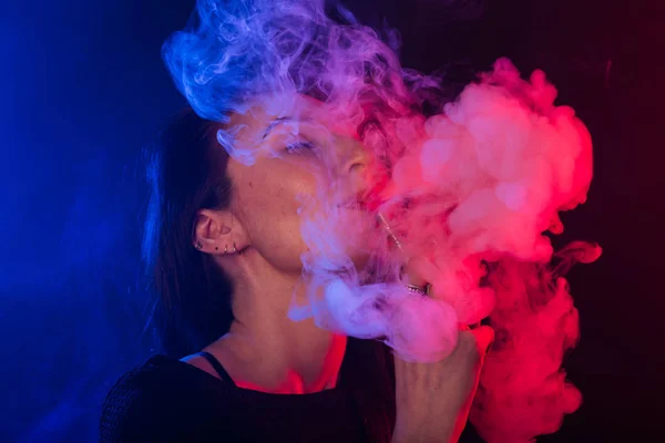 Retrato de mulher na fumaça de néon colorido com vape ou cigarro eletrônico — Fotografia de Stock