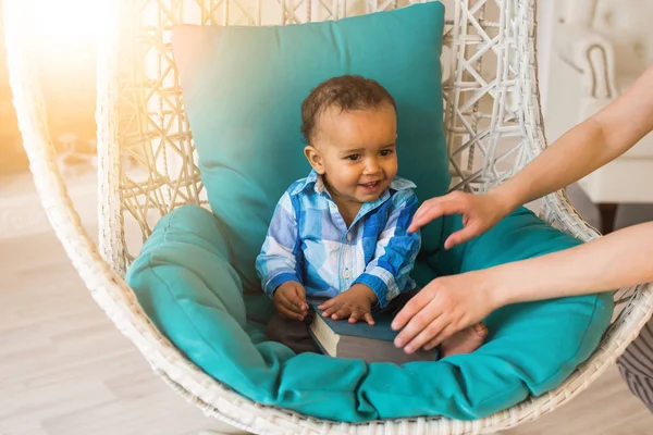 Retrato de niño afroamericano sosteniendo libro en silla . —  Fotos de Stock