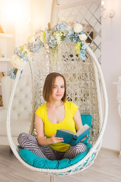 Jonge vrouw thuis zit op moderne stoel leesboek — Stockfoto