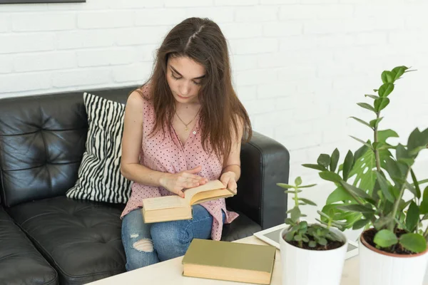 Istruzione e concetto di persone - giovane studentessa seduta sul divano buio con libro — Foto Stock