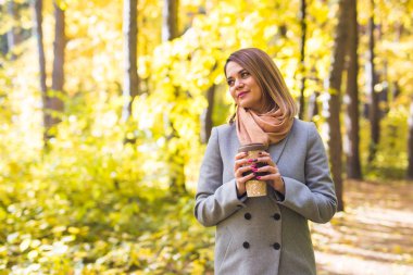 Sonbahar, Doğa ve insan kavramı - gri paltolu bir fincan tutan genç güzel kadın