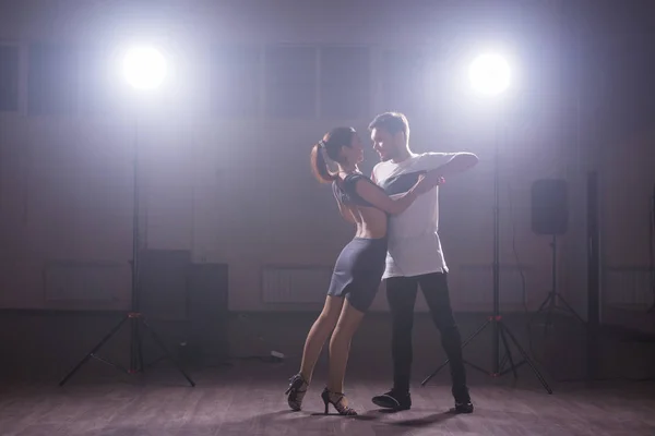 Casal jovem dançando danse social kizomba ou bachata ou semba ou taraxia em fundo de aula de dança — Fotografia de Stock