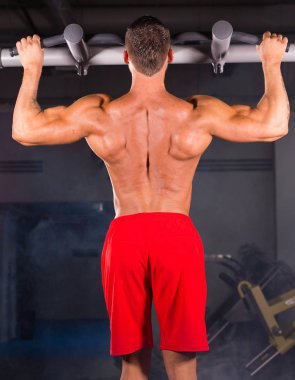 Yatay çubuk spor salonunda egzersiz yetişmek yapan güçlü genç erkek