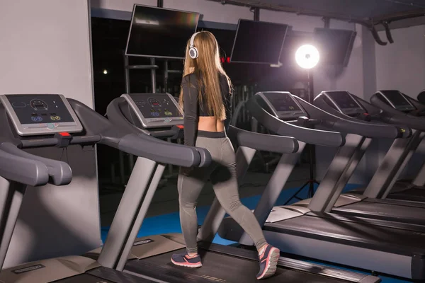 Fitness woman running on treadmill. Girl with muscular legs in gym — Stock Photo, Image