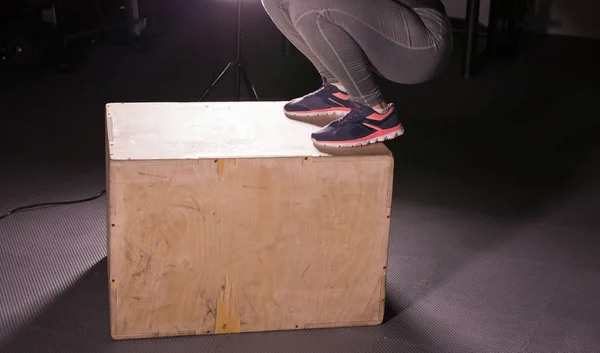 Mujer joven saltando en la caja en un gimnasio crossfit . — Foto de Stock