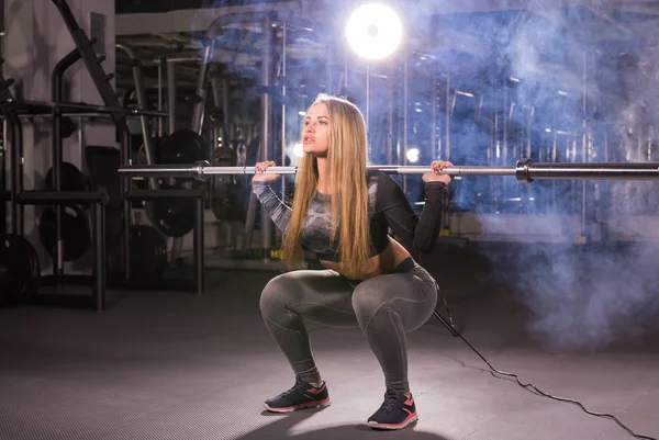 Güzel kadın bir spor salonunda barbell ile çalışma dışarı