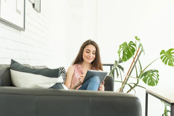 Personnes, concept intérieur et de loisirs - heureuse jeune femme avec tablette pc posée sur le canapé — Photo
