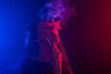 Asyalı kadın sigara vape veya e-sigara neon ışık siyah arka plan, portre.