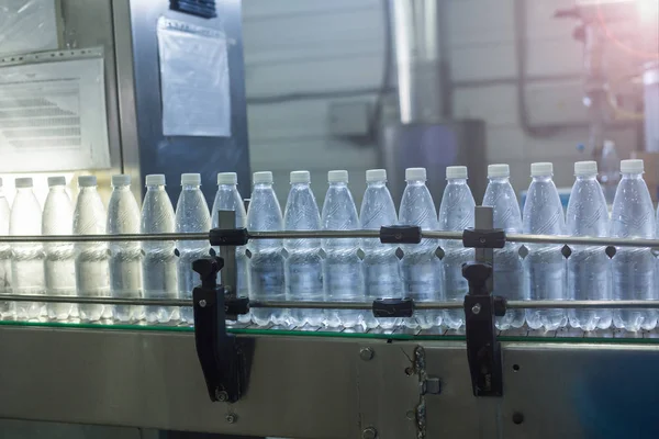Wasserflaschen am Fließband. Mineralwasser in kleine Flaschen abfüllen — Stockfoto