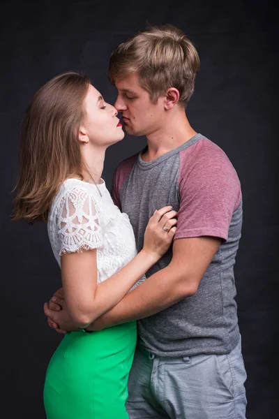 Älskare som kysser varandra på svart bakgrund — Stockfoto