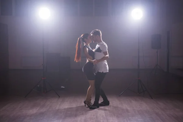 Dançarinos habilidosos se apresentando na sala escura sob a luz do concerto e fumaça. Casal sensual realizando uma dança contemporânea artística e emocional — Fotografia de Stock