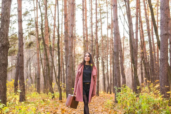 Seizoen, de natuur en de mensen concept - vrouw in herfst park poseren met koffer — Stockfoto