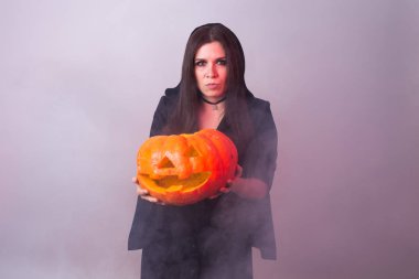 Halloween cadı bir turuncu kabak Jack o fener duman ile tutarak
