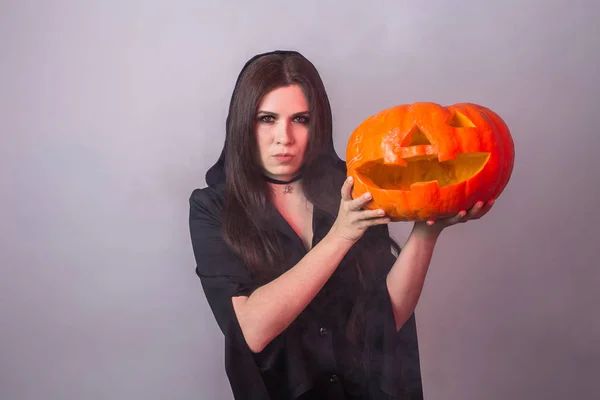 Sorcière d'Halloween tenant une citrouille orange Jack o Lanterne avec fumée — Photo