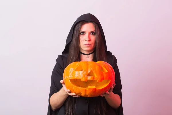Młoda kobieta w Halloween czarownica kostium w studio z pumpkin żółty. — Zdjęcie stockowe