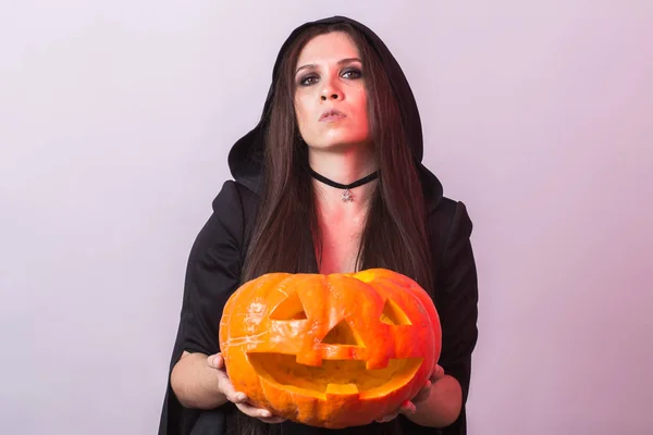 Young woman in Halloween witch costume in studio with yellow pumpkin. — Stock Photo, Image