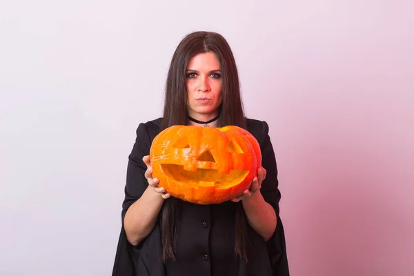 Готическая молодая женщина в костюме ведьмы на Хэллоуин с резной тыквой — стоковое фото
