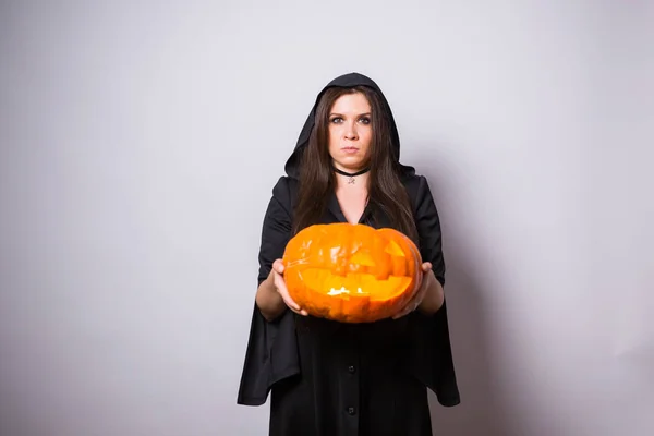 Gotische junge Frau im Hexen-Halloween-Kostüm mit geschnitztem Kürbis auf weißem Hintergrund mit Kopierraum — Stockfoto