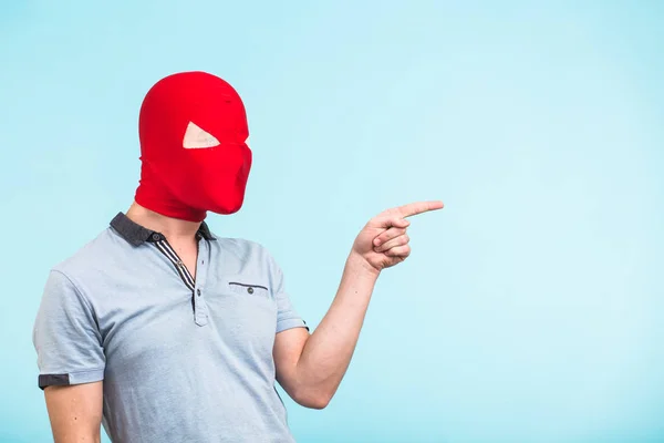 파란색 배경 복사 공간에 가리키는 입고 빨간 마스크 남자. 익명 사회 보호 개념입니다. 할로윈 — 스톡 사진