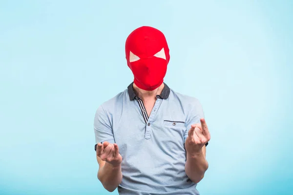 Muž na sobě červenou masku na modrém pozadí. Koncept anonymní sociální maskování. Halloween — Stock fotografie