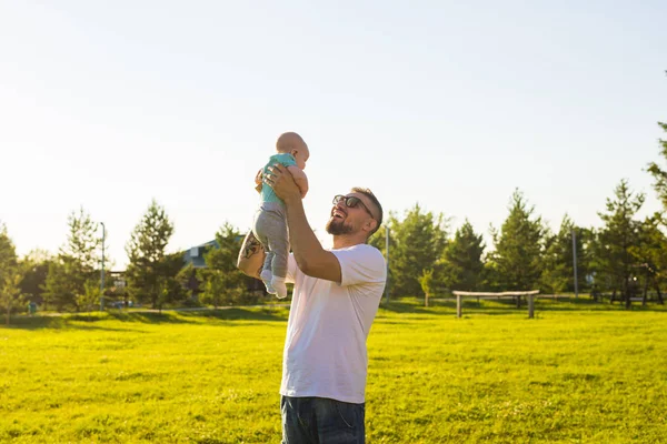 Heureux père tenant bébé fils, jetant bébé dans l'air. Concept de famille heureuse, fête des pères et des enfants . — Photo