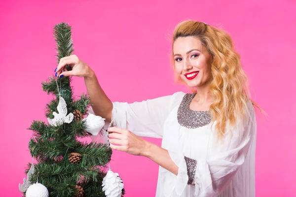 Χριστούγεννα, διακοπές και άνθρωποι έννοια - νέοι ευτυχισμένη γυναίκα ξανθιά διακόσμηση του Χριστουγεννιάτικου δέντρου σε ροζ φόντο — Φωτογραφία Αρχείου